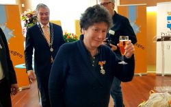 Anita Verheggen prooost met haar glas richting de camera. Op de achtergrond de burgemeester.